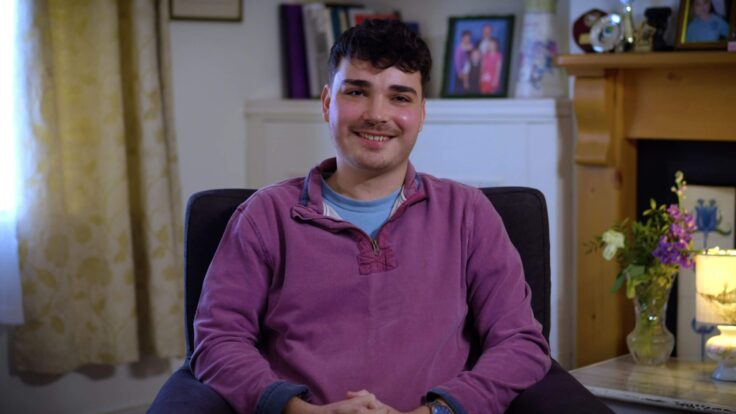 Elliott's story is told by a young man sitting in an armchair, wearing a purple sweatshirt.