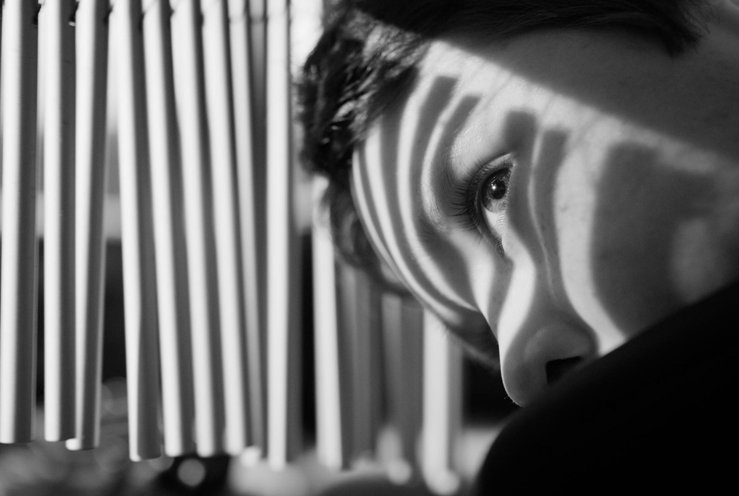 A still from Through Their Eyes film in black and white. It shows Charlie looking at chimes in the music room at Haven House