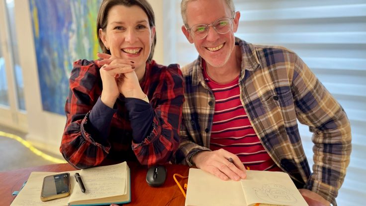 Dan Mellor and Pip Evan-Cook doing a review of Christmas Ads 2025. They are both middle-aged and smiling, wearing checked shirts and looking festive.