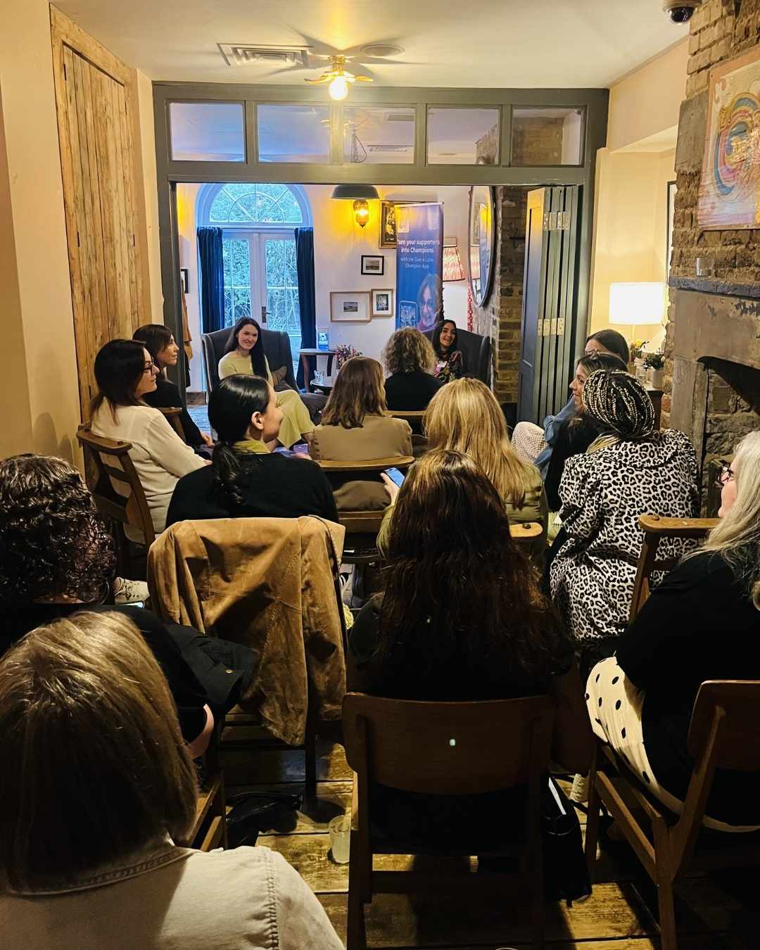 A scene from the back of the room at the MOREVER Meetup. Abi Mellor and Laura Mitchell are seated in front of an audience of around 30 women who are listening intently to what they are saying.